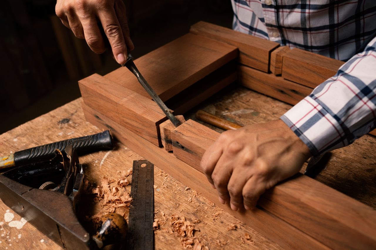 about-us Detailed view of hands using a chisel in woodworking, creating precise craftsmanship.